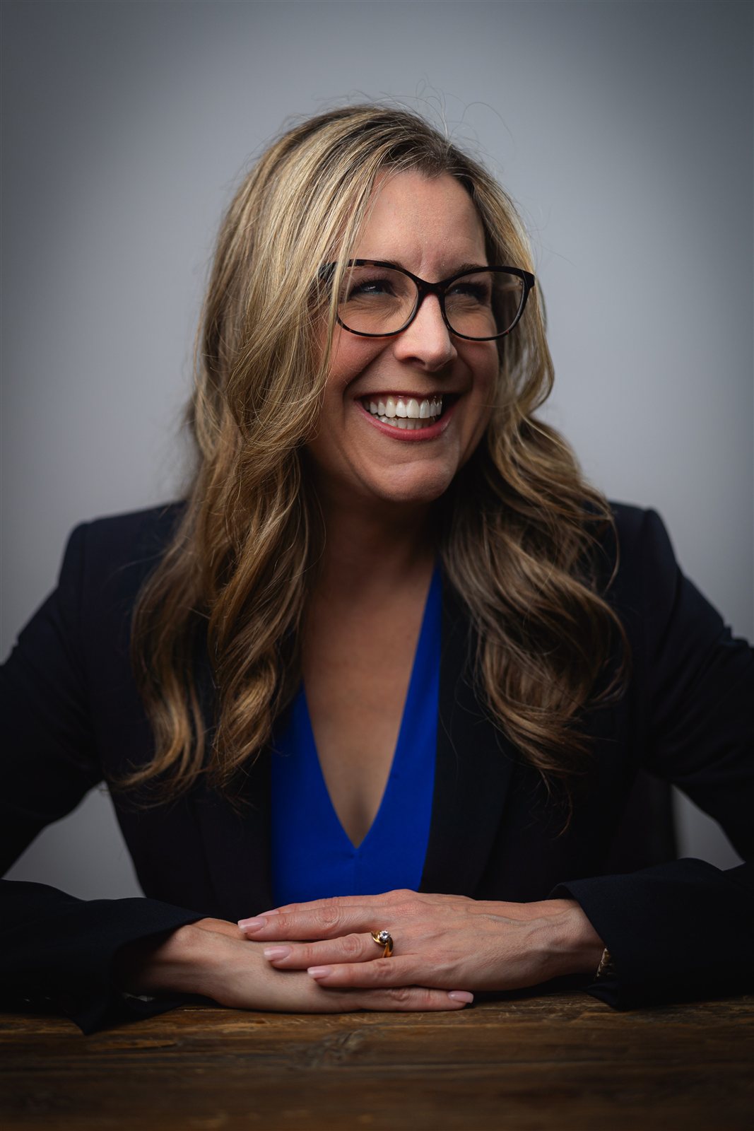 Jennifer Davis seated at a table, laughing, in a navy blazer